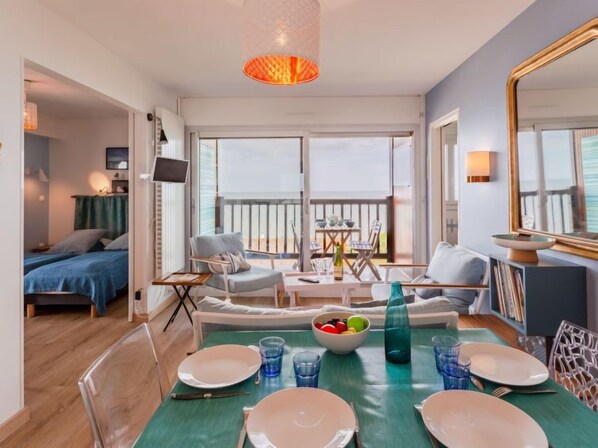 A modern, well-lit room with a dining area, a balcony, and a bed.