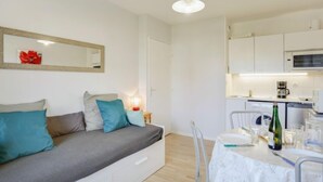 A modern, compact living space with a sofa, a dining table, and a kitchen area. - Fleur Marine by Interhome (Cabourg)