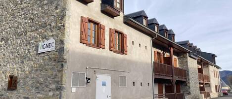 A stone building with wooden shutters, a sign reading "VIGNEC," and a door with a window.