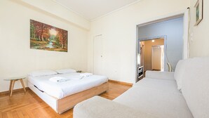 A hotel room with two beds, a small table, and a painting on the wall. - Victoria Secret apartment (Athina)