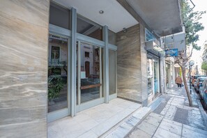 Une façade d’immeuble avec de grandes fenêtres en verre, une entrée carrelée et une devanture visible.