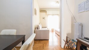A room with a wooden floor, a sofa, a table, and a radiator. - Victoria Secret apartment (Athina)