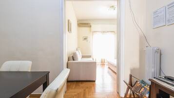 Een kamer met houten vloer, een bank, een tafel en een radiator.