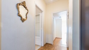 A hallway with wooden flooring, white walls, and a gold-framed mirror. - Victoria Secret apartment (Athina)