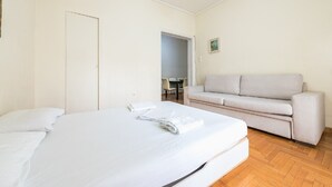 A bedroom with a bed, a sofa, and a door leading to a dining area. - Victoria Secret apartment (Athina)