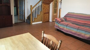 A living room with a wooden staircase, a sofa, and a dining table.