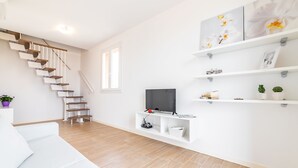 Un salon moderne avec un escalier, des murs blancs et un plancher en bois.