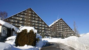 Lumipeitteinen rakennus, jossa on moderni arkkitehtoninen ilme, useita kerroksia ja huomiota herättävä kolmiomainen katto.