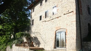 Un bâtiment en pierre doté d’une terrasse en bois et d’une porte vitrée.