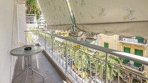 A balcony with a table and chairs, a view of the street below, and a building with a sign in Greek. - Victoria Best Apartments # 3 (Athina)