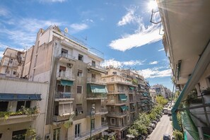 Ein mehrstöckiges Wohngebäude mit Balkonen, eine Straße davor und ein klarer Himmel.