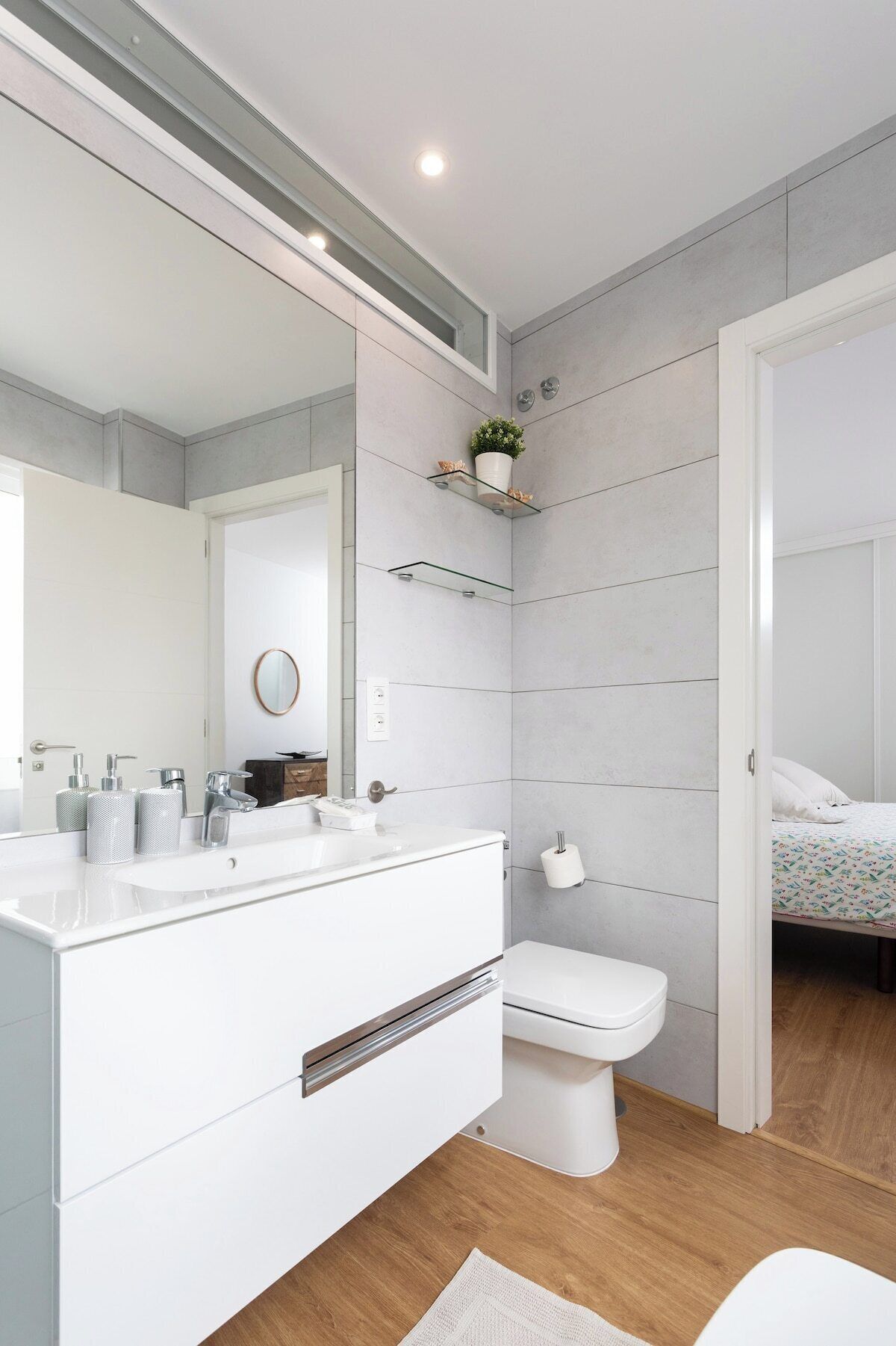 A modern bathroom with a white vanity, a toilet, and a shower area.