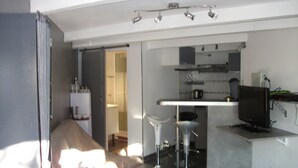 A modern kitchen with a bar area, a television, and a seating area with stools.