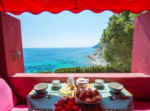 Una mesa dispuesta con alimentos para el desayuno y vistas al mar.