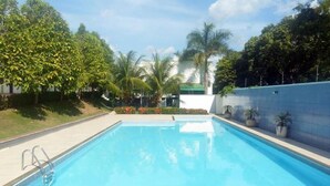 A rectangular swimming pool with a clear blue water surface, surrounded by a tiled deck and a low wall.