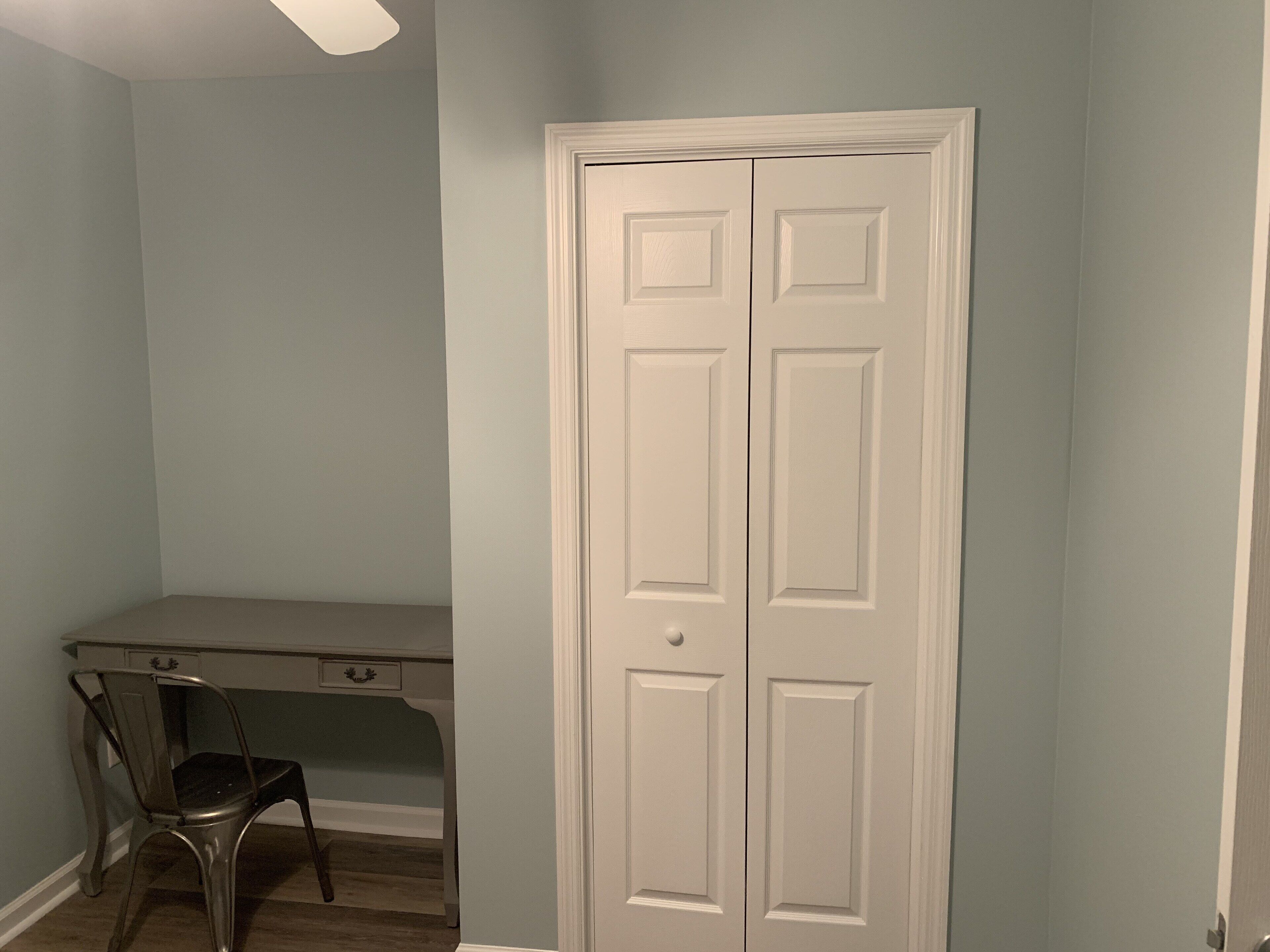 A room with a desk, chair, and a white door.