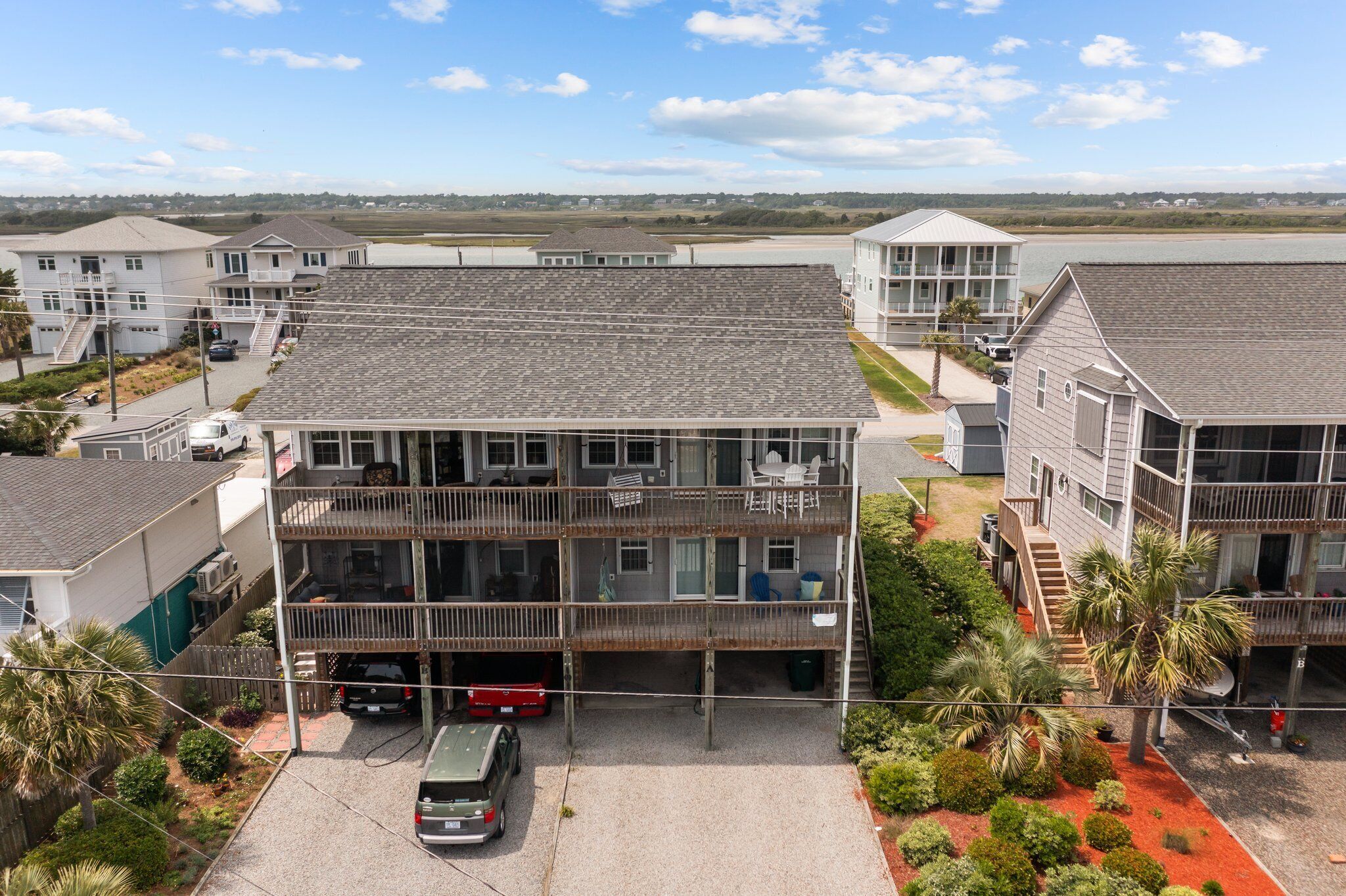 A multi-story building with a parking area and a view of a body of water.