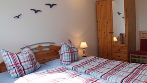 Un dormitorio con dos camas, un armario de madera, un espejo y adornos en la pared.