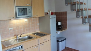 Una cocina compacta equipada con microondas, lavabo y un refrigerador pequeño.