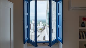 A room with a view through an open blue door, a white wall, and a bookshelf with books and a vase. - Terrazza Blu Cobalto by Wonderful Italy (Ostuni)