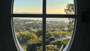 A large circular window with a clear view of a green landscape and distant hills.
