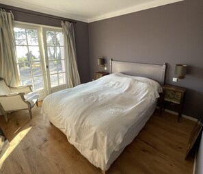 A bedroom with a large bed, two bedside tables, a chair, and a window with curtains. - Idyllic vacation dream (Cavalaire-sur-Mer)
