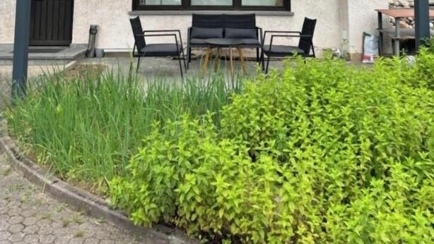Un bâtiment à deux étages doté d’un balcon, de grandes fenêtres et d’un espace extérieur abrité avec des chaises, aménagé pour s’y asseoir.