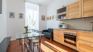 A modern kitchen with wooden cabinets, a microwave, and a dining area with a glass table and chairs.