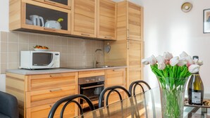 A modern kitchen with wooden cabinets, a microwave, a sink, and a dining table with chairs.