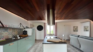 Una cocina moderna con una isla central, una zona de comedor con un sofá y un ventanal con cortinas.