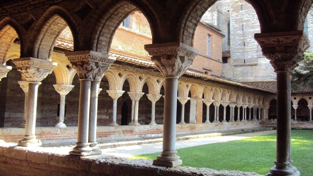 Un patio interior con una serie de arcos y columnas, que sugieren un edificio histórico o religioso.