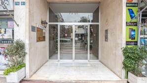 A building entrance with a glass door, a sign with the number 79 81, and a service advertisement on the right. - Victoria Capitan Apartments (Athina)