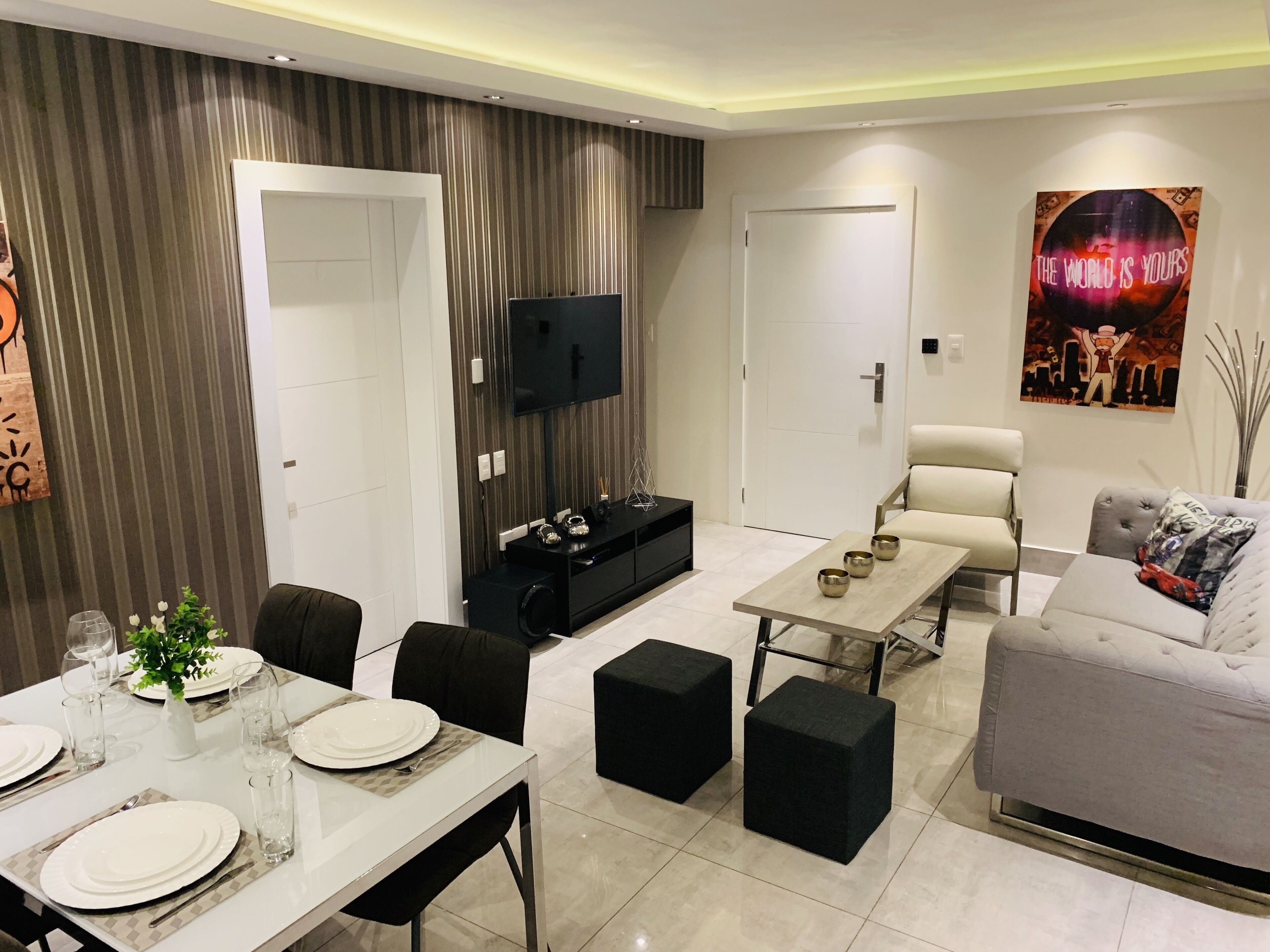 A modern living room with a dining area, a flat-screen TV, a sofa, and a coffee table.
