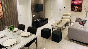 Una sala de estar moderna con comedor, un televisor de pantalla plana, un sofá y una mesa de centro.
