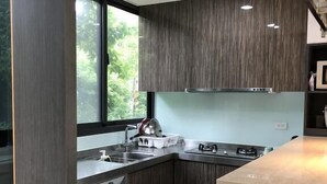 A modern kitchen with dark wood cabinets, a stainless steel sink, and a built-in oven. - Ming Yueju (Guoxing)