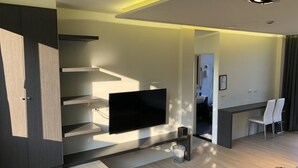 A modern living room with a flat-screen TV mounted on the wall, a wooden coffee table, and a dining area with chairs. - Ming Yueju (Guoxing)