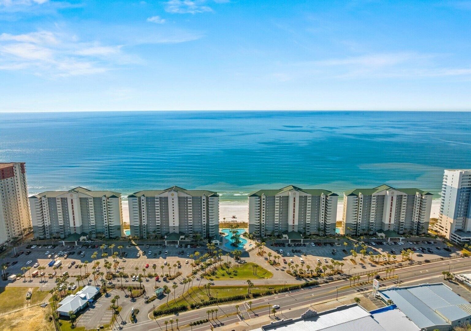 A high-rise hotel with multiple balconies overlooking a beach and ocean.