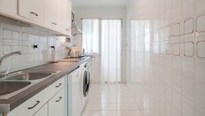 A modern kitchen with white cabinets, stainless steel appliances, and a built-in washing machine. - Bright 3 Bed, Sea Views Beach Apt (Benalmádena)