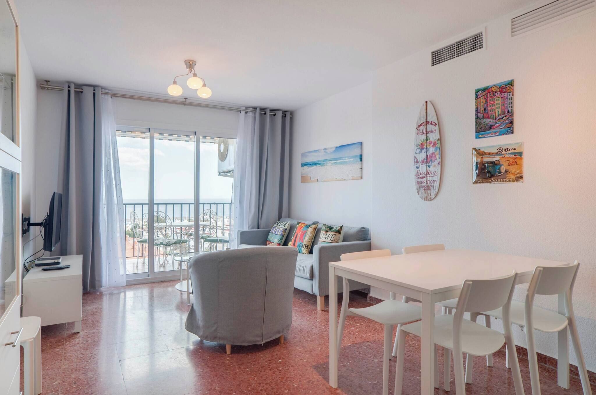 Un salon moderne avec un balcon, un coin repas et un canapé agrémenté de coussins colorés.