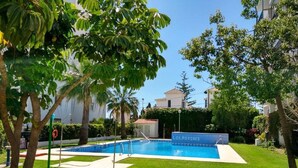 A swimming pool with a sign reading "LOS PORCHES" surrounded by well-maintained grass and trees. - Bright 3 Bed, Sea Views Beach Apt (Benalmádena)
