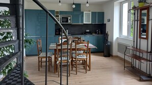 A modern kitchen with teal cabinets, a dining table with chairs, and a staircase with a metal railing. - The house of La Digue, 2 bedrooms with terrace and parking (Blois)
