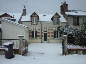 A residential building with a snow-covered entrance, brick facade, and multiple windows.