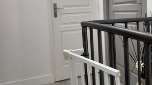 A hallway with a white door, a black and white railing, and a painting on the wall. - The house of La Digue, 2 bedrooms with terrace and parking (Blois)