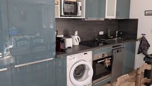 A compact kitchen with a washing machine, a microwave, and a sink. - The house of La Digue, 2 bedrooms with terrace and parking (Blois)