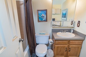 Un baño con inodoro, lavamanos y armarios de madera.
