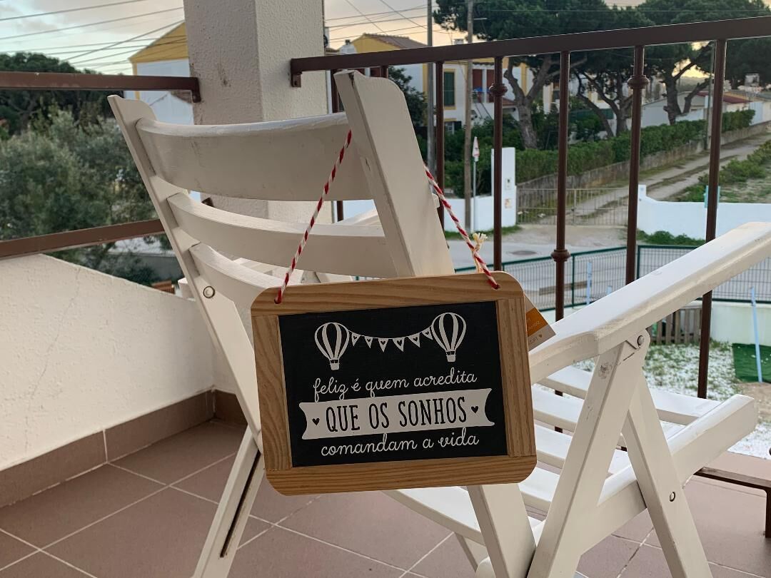 A balcony with a white chair and a sign with a motivational quote.