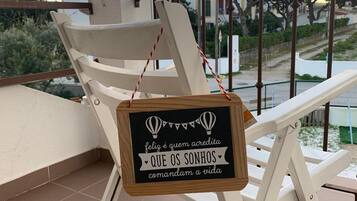 A balcony with a white chair and a sign with a motivational quote.