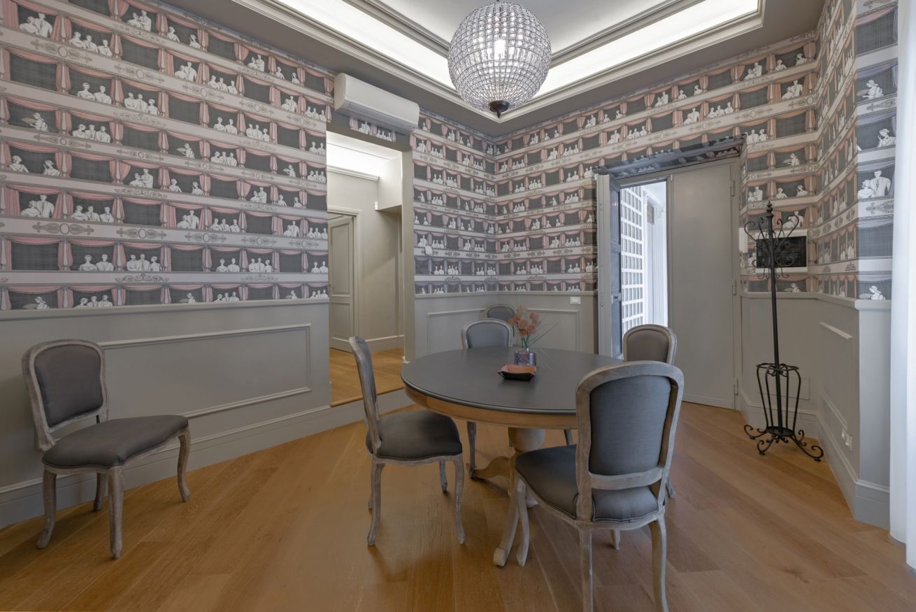 Une salle à manger avec un lustre, une table ronde et des chaises.