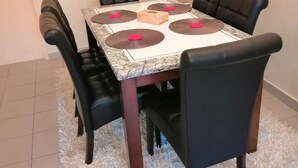 Ein Essbereich mit einem quadratischen Tisch, vier schwarzen Stühlen und einem weißen Shaggy-Teppich.