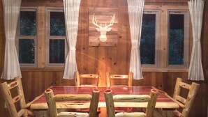 A wooden interior with a dining table, chairs, and curtains.
